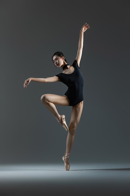 Photo a beautiful young dancer is dancing ballet in the studio with a beam of light