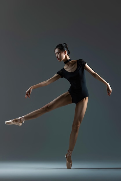 Photo a beautiful young dancer is dancing ballet in the studio with a beam of light