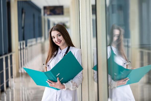 Beautiful young doctor is standing in the hospital corridor with a stethoscope around her neck