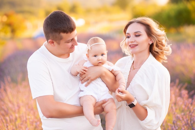 Beautiful young family, father and mother with baby on lavander field