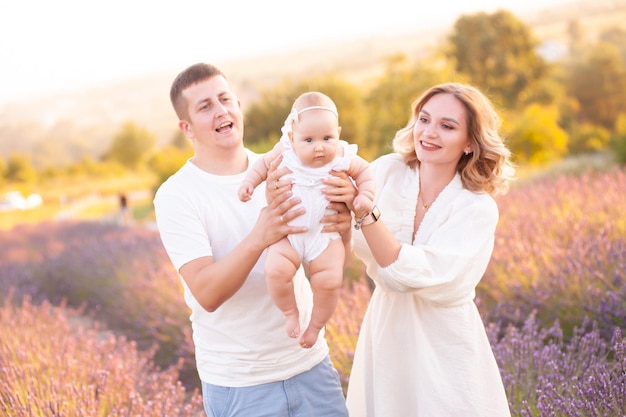 Beautiful young family, father and mother with baby on lavander field