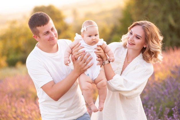 Beautiful young family, father and mother with baby on lavander field