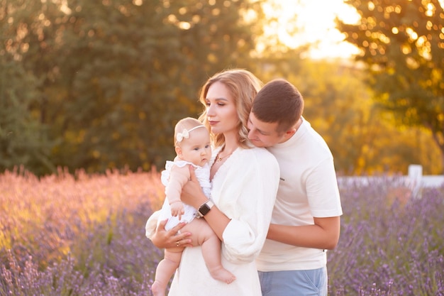 Beautiful young family, father and mother with little daughter playing on lavander field