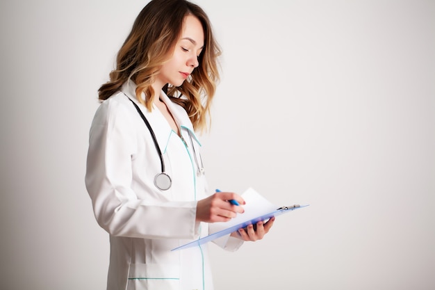 Beautiful young female doctor in a white coat watching a patient's card