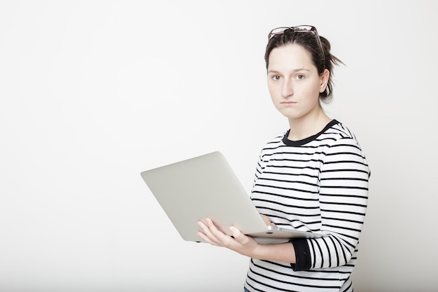 Beautiful young female student with glasses is very serious and holding a laptop in hands