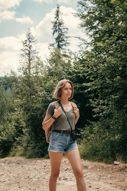 Beautiful young female traveler with backpack walking by the mountain footpath