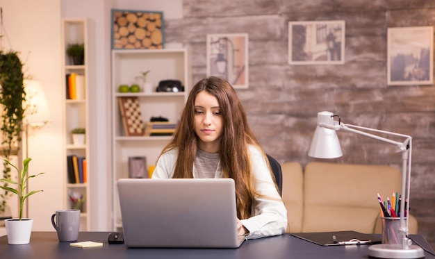 Beautiful young female working on laptop in home office. Young freelancer working from home.