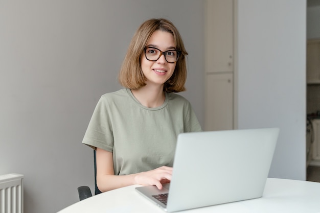 Beautiful Young Freelancer Woman Using Laptop Computer sitting at the office table. Freelance Work, online education Concept