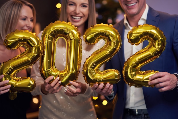 Beautiful young friends having fun at New Year's Eve Party holding numbers 2022