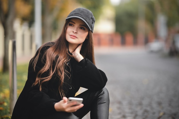 Beautiful young girl in a baseball cap with a smartphone in her hands