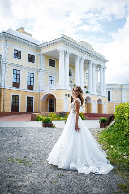 Beautiful young girl bride in a white wedding dress with a train walks in the park