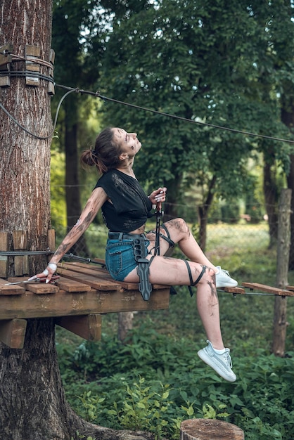 Beautiful young girl in dirty ragged clothes with swords and knives in the woods trains