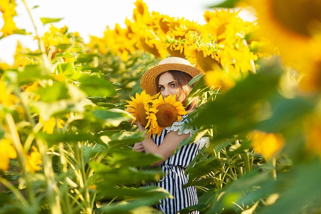 Beautiful young girl enjoying nature on the field of sunflowers at sunset