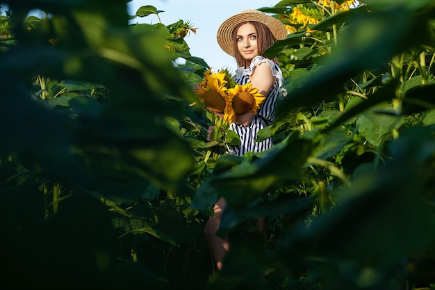 Beautiful young girl enjoying nature on the field of sunflowers at sunset