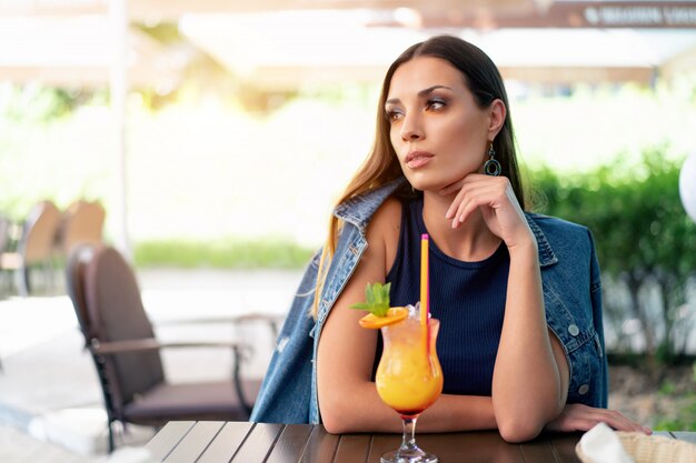 A beautiful young girl of European appearance is drinking an exotic summer cocktail 