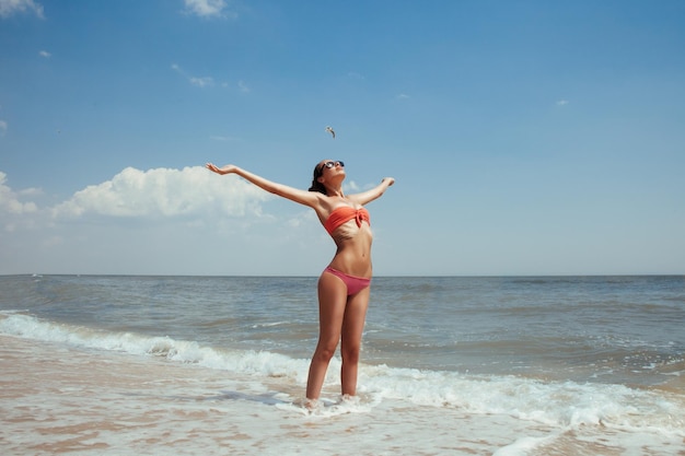 Beautiful young girl flying with seagulls on the sea the girl in sunglasses and a swimsuit He smiles and enjoys sea and sun