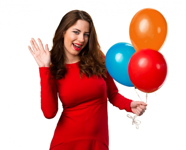 Beautiful young girl holding balloons and saluting