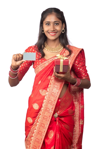 Beautiful young girl holding and posing with a gift box with a credit or debit card on a white background