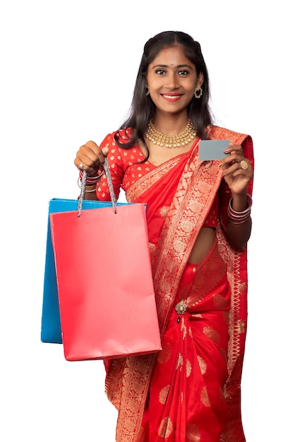 Beautiful young girl holding and posing with shopping bags and credit or debit card on a white background