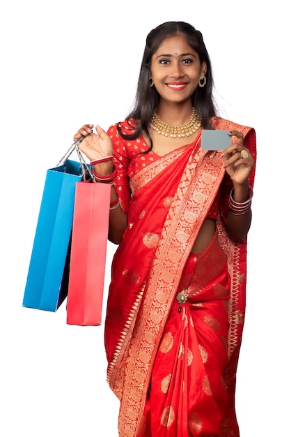 Beautiful young girl holding and posing with shopping bags and credit or debit card on a white background