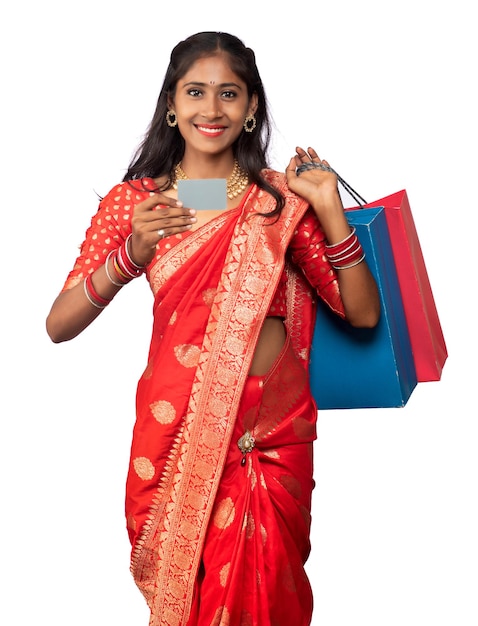 Beautiful young girl holding and posing with shopping bags and credit or debit card on a white background