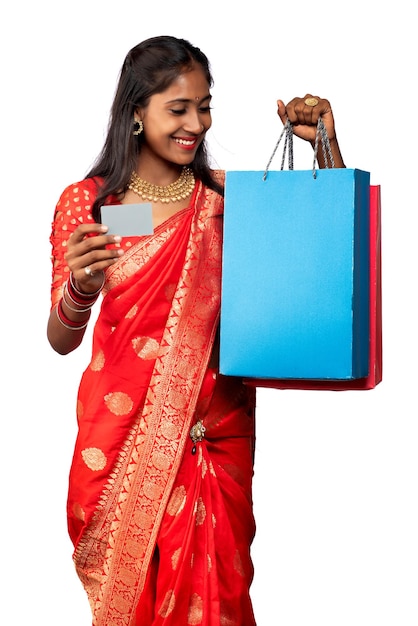 Beautiful young girl holding and posing with shopping bags and credit or debit card on a white background