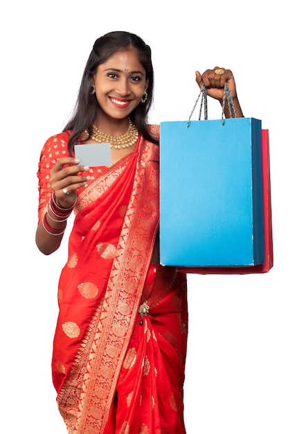 Beautiful young girl holding and posing with shopping bags and credit or debit card on a white background