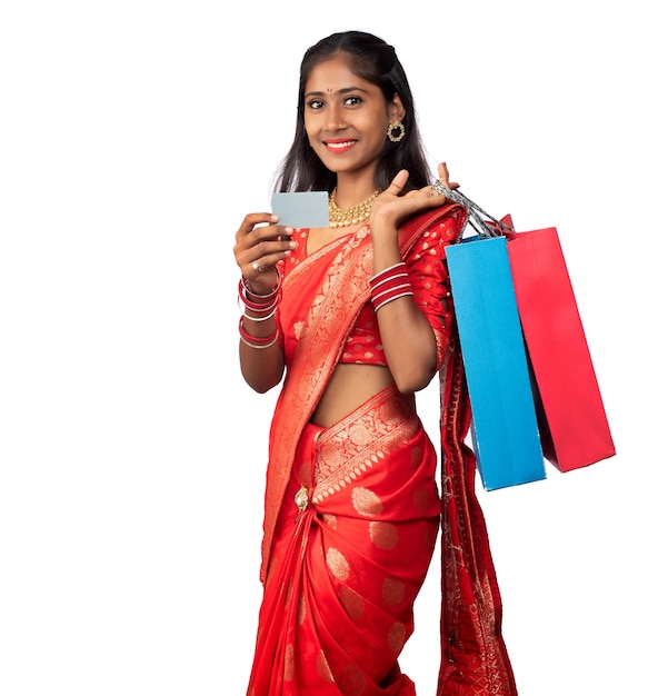 Beautiful young girl holding and posing with shopping bags and credit or debit card on a white background