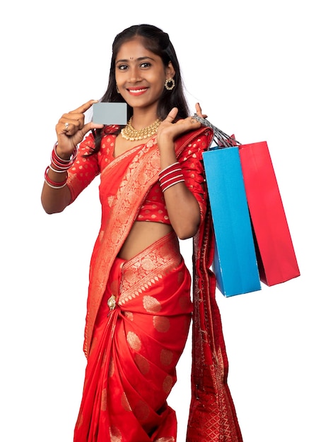 Beautiful young girl holding and posing with shopping bags and credit or debit card on a white background