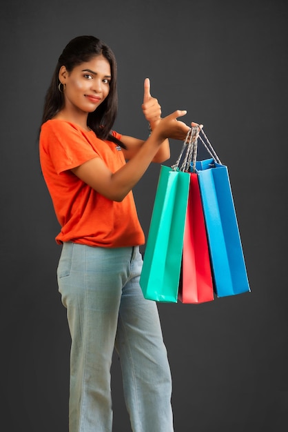 Beautiful young girl holding and posing with shopping bags on a grey background