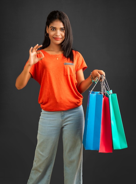 Beautiful young girl holding and posing with shopping bags on a grey background