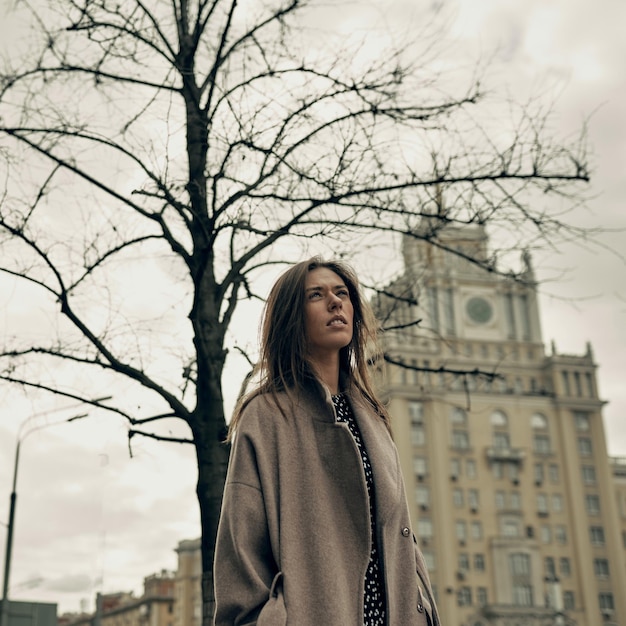 A beautiful young girl is walking in the city in autumn. Spring in the city. Beauty. thunderclouds.