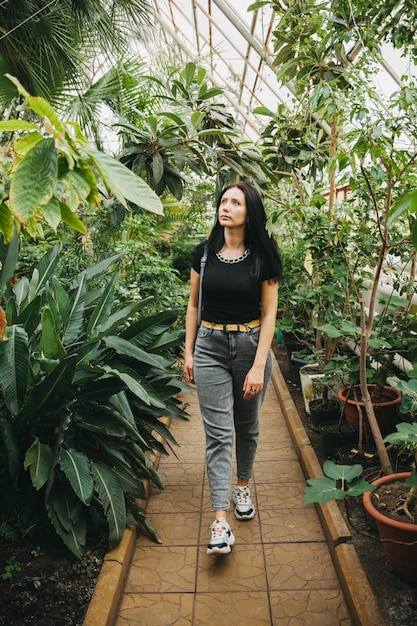 A beautiful young girl is walking through the greenhouse Woman in the botanical garden