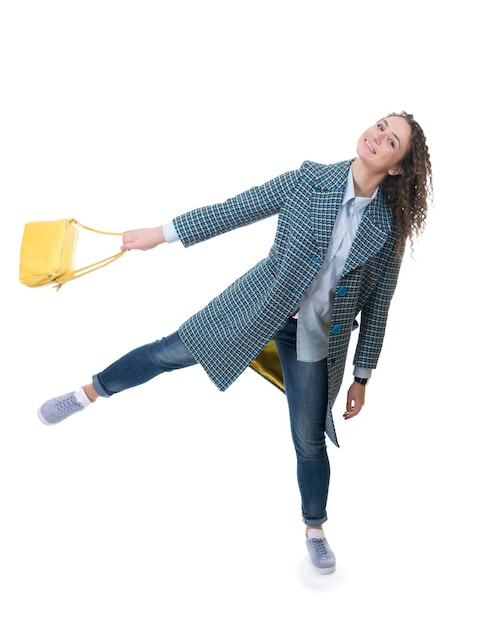 Beautiful young girl in a light coat with a yellow bag walks with yellow balloons