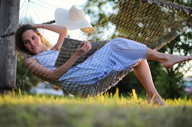 Beautiful young girl lying and reading a book in the summer outdoors