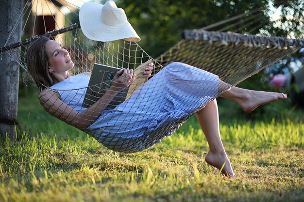 Beautiful young girl lying and reading a book in the summer outdoors