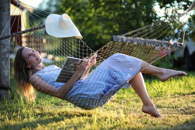 Beautiful young girl lying and reading a book in the summer outdoors