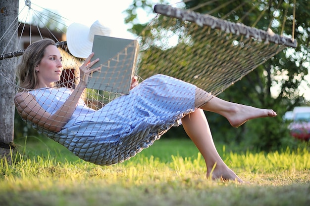 Beautiful young girl lying and reading a book in the summer outdoors