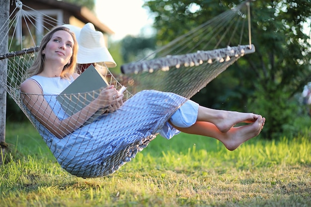 Beautiful young girl lying and reading a book in the summer outdoors