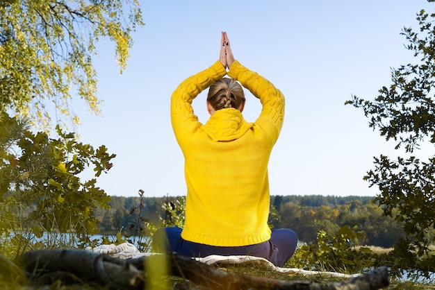 Photo beautiful young girl meditating in autumn park woman meditates in the forest