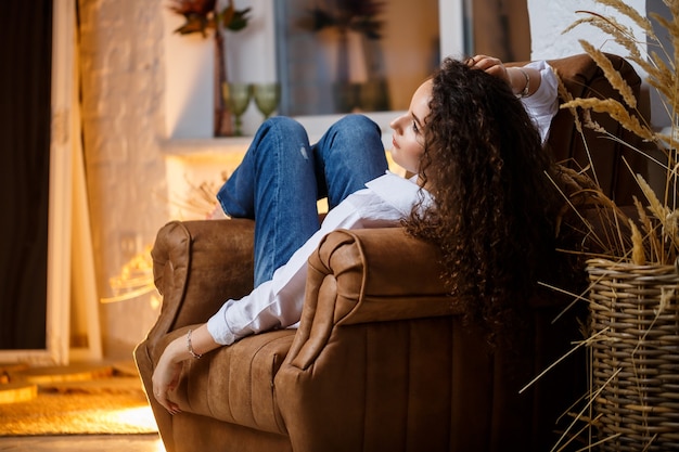 Photo beautiful young girl model with curls posing. she is wearing a white shirt and jeans.