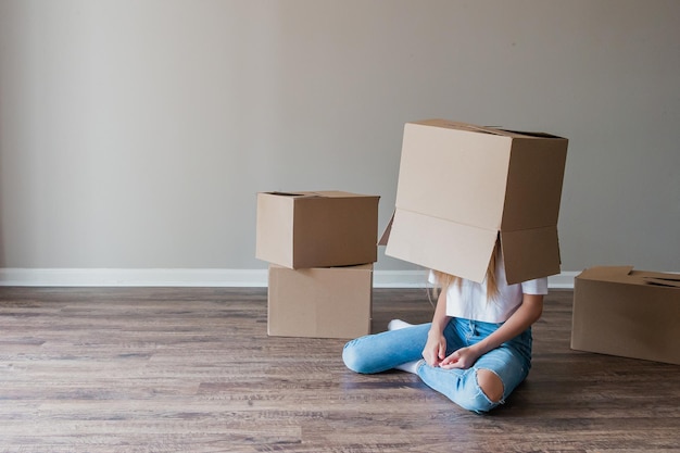 Photo beautiful young girl moving in new house with cardboard boxes