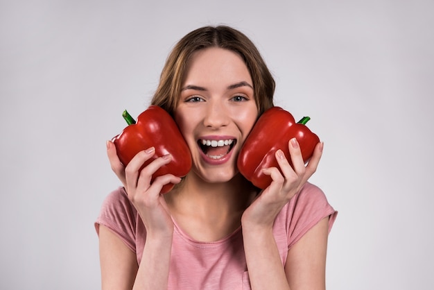 Beautiful young girl playing with red pepper.