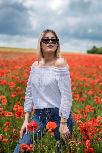 Beautiful young girl in the poppy field. She spending free time and good weather for enjoys