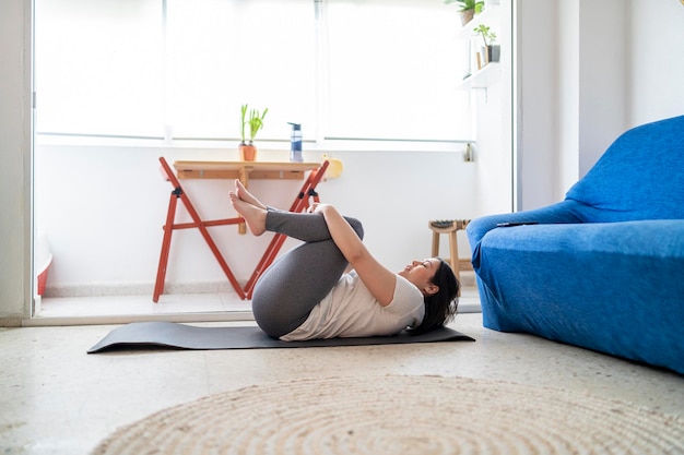 beautiful young girl practicing exercise in the living room of her house with her black cat