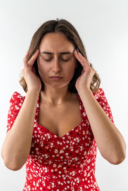 Beautiful young girl in a red dress holds her head and feels pain headache migraine