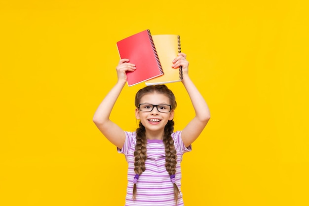 A beautiful young girl shows notebooks A child in a striped Tshirt