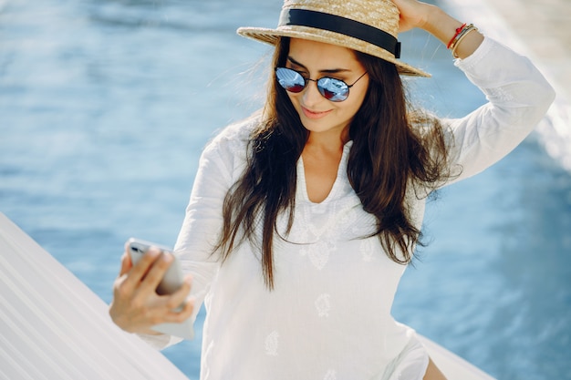 A beautiful young girl sitting on a summer terrace by the pool with phone