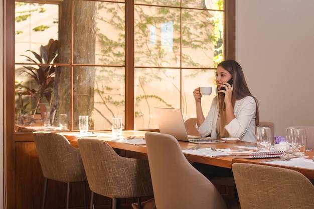 Beautiful young girl sitting talking on the phone while drinking coffee