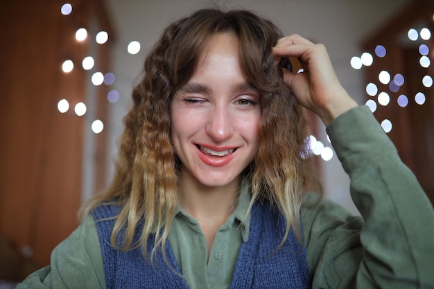 A beautiful young girl smiles and holds her hands to her face The girl props her chin with her